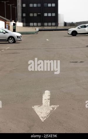 frecce dipinte di bianco sul pavimento del parcheggio per dirigere il traffico Foto Stock