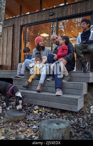 Famiglia che parla e rilassarsi sul patio della cabina Foto Stock