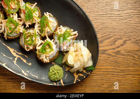 Un set di sushi caldi con salmone, avocado e semi di sesamo nero da vicino. Fuoco selettivo Foto Stock