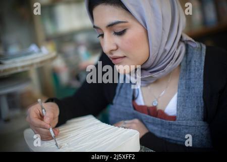 Giovane artista femminile in hijab che lavora in studio d'arte Foto Stock