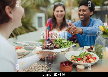 Amici felici che godono il pranzo vegetariano al tavolo del patio Foto Stock