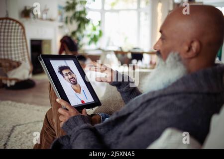 Uomo anziano che parla con il medico sullo schermo del tablet digitale Foto Stock