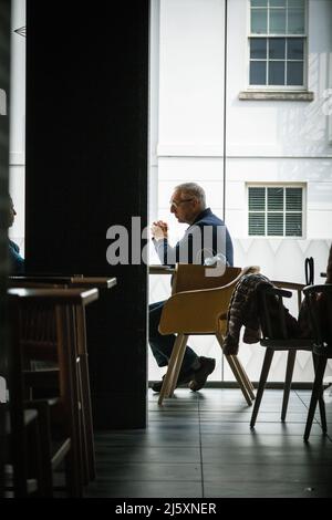 Uomo solitario e attento, di mezza età, che si rilassa in una caffetteria Foto Stock