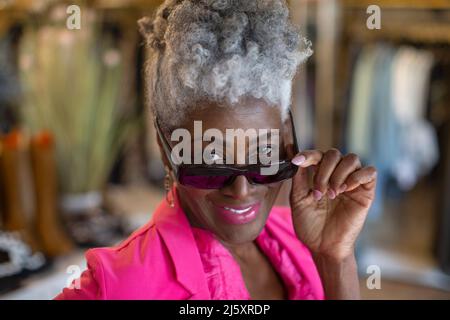Primo piano ritratto sorridente donna anziana con occhiali da sole Foto Stock