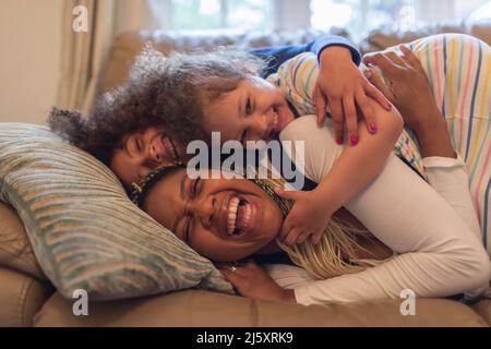 Ritratto felice mamma e bambini giocosi sul divano Foto Stock