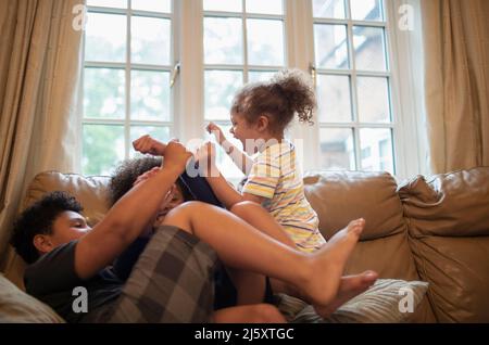 Fratello e sorelle giocosi sul divano del soggiorno Foto Stock