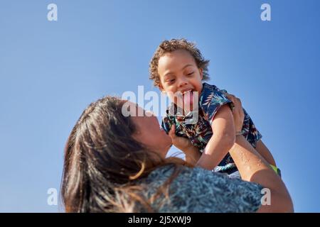 Madre sollevamento figlio felice con sindrome di Down Foto Stock