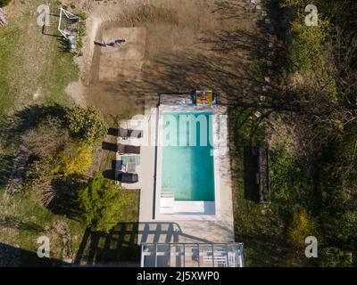 Volo con droni su un'area di terra fresca con erba coltivata accanto al cantiere di costruzione della piscina nel mese di aprile Foto Stock