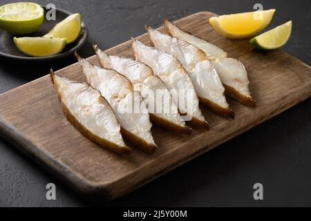 Deliziose fette di halibut affumicate servite con lime su sfondo nero. Primo piano. Spazio di copia. Foto Stock