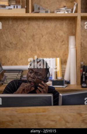 Uomo d'affari con cuffie in ufficio Foto Stock