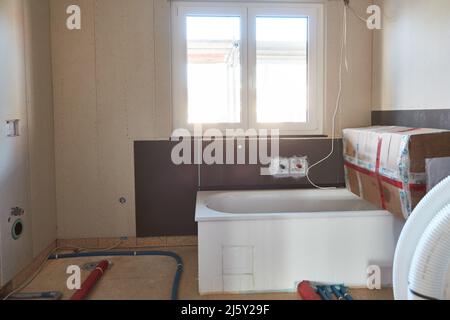 Bagno con vasca da bagno come cantiere con materiali da costruzione quando si costruisce una casa Foto Stock