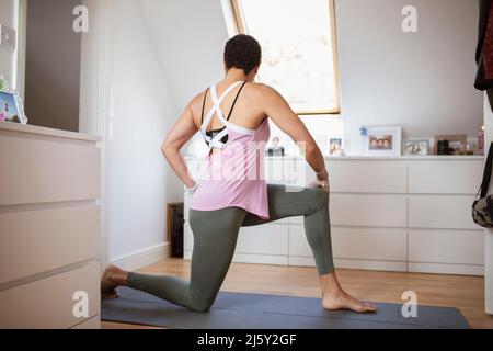 Donna che si esercita, pratica yoga twist su tappeto a casa Foto Stock