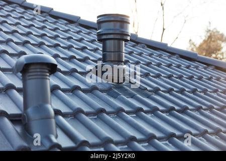 Tubo di ventilazione e piccolo camino sul tetto di una nuova casa Foto Stock