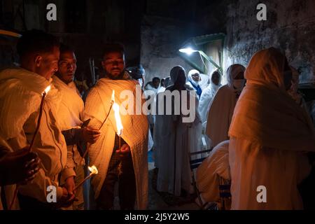 I cristiani ortodossi etiopi tengono candele mentre prendono parte alla cerimonia del fuoco Santo nel monastero di Deir El-Sultan adiacente alla Chiesa del Santo Sepolcro il 23 aprile 2022 a Gerusalemme, Israele. I cristiani etiopi commemorano gli eventi attorno alla crocifissione di Gesù Cristo, portando alla sua risurrezione nella Pasqua, che in lingua amarica viene chiamata Fasika. Foto Stock