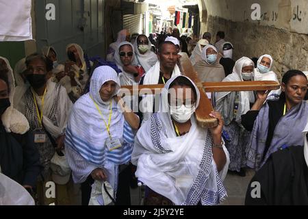 I cristiani ortodossi etiopi portano una grande croce di legno mentre camminano lungo Via dolorosa durante la processione ortodossa del Venerdì Santo il 22 aprile 2022 a Gerusalemme, Israele. Ebrei, cristiani e musulmani celebrano la Pasqua di quest'anno e il Ramadan nella stessa settimana. Foto Stock