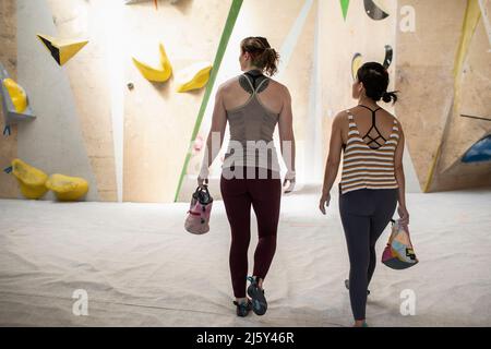 Scalatori di roccia femminile con sacche di gesso in centro di arrampicata Foto Stock
