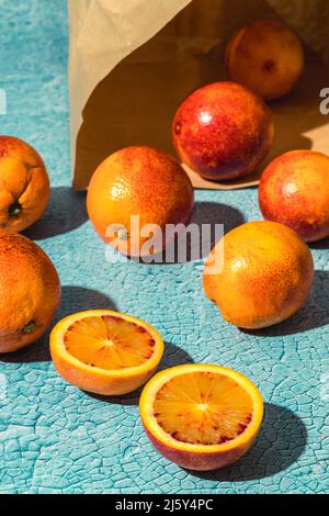 Mucchio di arance fresche mature con macchie rosse sparse su sfondo chiaro con sacchetto di carta in camera Foto Stock