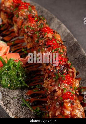 Da sopra di appetitosi sushi roll con caviale rosso e salmone serviti su piatto con insalata di wakame nel ristorante Foto Stock