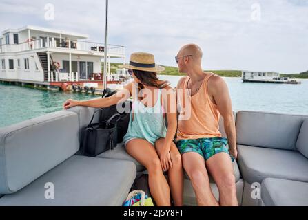 Coppia rilassante sul catamarano, guardando oltre la spalla a houseboat Foto Stock