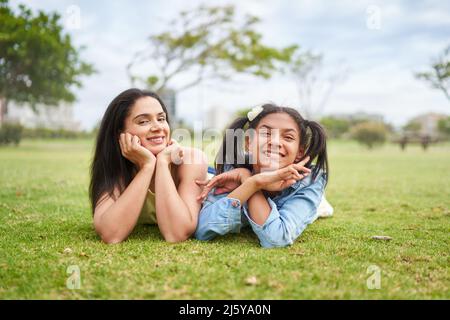 Ritratto felice brunette madre e figlia che posano in erba parco Foto Stock