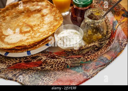 Pancake, yogurt, marmellata di lamponi e yogurt, sciarpa rossa sul tavolo, primo piano. Dolce dessert, colazione o snack. Foto Stock