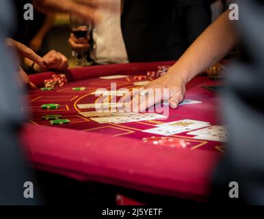 Carte di mano femminile caucasica su un tavolo rotondo rosso da casinò. Foto Stock