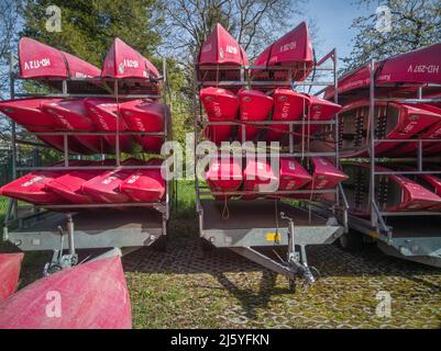 Neckargemuend, Germania: 11 aprile 2022: Canoe rosse su un rimorchio auto in primavera in attesa di essere utilizzato per tour turistici sul fiume in estate Foto Stock