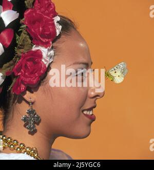 Una farfalla cerca di atterrare su una bella ragazza senorita messicana con fiori nei suoi capelli, Cabo San Lucas, Baja Mexico Foto Stock