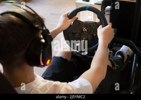 Mani di un Teeneger su un volante, mentre gioca un gioco di corse Foto Stock