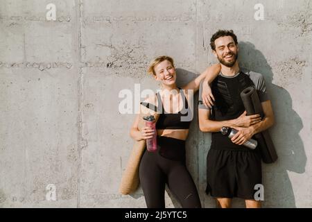Giovane uomo e donna sorridenti mentre si allenano insieme nel parcheggio all'aperto Foto Stock