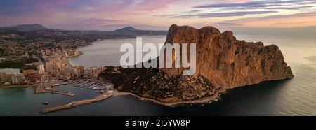 Pittoresca alba multicolore sulla città di Calpe e il Parco Naturale Penyal d Ifac. Orizzonte sulle acque di mare Mediterraneo calmo. Spagna Foto Stock