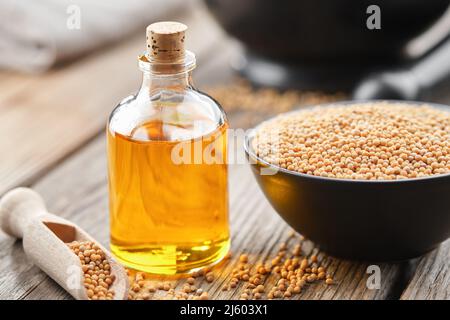 Bottiglia di olio naturale di senape organica e ciotola di senape di grano intero. Foto Stock