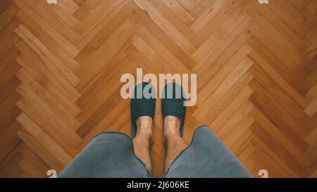 Uomo casual che indossa ciabatte a casa in piedi in camera da letto su parquet di quercia, vista dall'alto con spazio copia Foto Stock