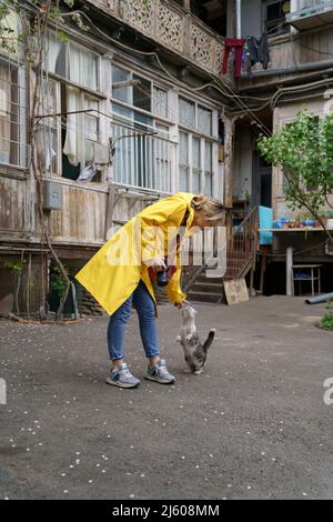 Giovane fotografa che gioca con il gatto per strada nella città vecchia Foto Stock