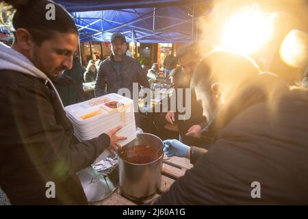 26 aprile 2022, Hessen, Francoforte sul meno: I dipendenti consegnano cibo al Bahnhofsviertel durante la rottura del digiuno del 5th organizzata dall'iniziativa gemeinsames Fastenbrechen. Nella sezione di Elbestraße tra Münchenerstrasse e Kaiserstraße, gli uomini d'affari e i ristoranti locali invitano la gente a condividere un pasto. Il mese del digiuno islamico del Ramadan continua fino alla sera del 1 maggio 2022. Foto: Sebastian Gollnow/dpa Foto Stock