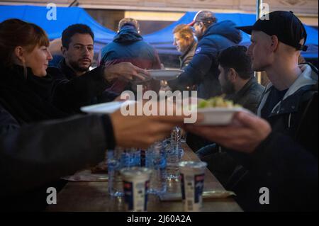 26 aprile 2022, Hessen, Francoforte sul meno: La gente passa il cibo l'una all'altra durante la rottura 5th del digiuno dell'iniziativa gemeinsames Fastenbrechen nel Bahnhofsviertel. Nella sezione Elbestraße tra Münchenerstrasse e Kaiserstraße, gli uomini d'affari e i ristoranti locali invitano la gente a condividere un pasto. Il mese del digiuno islamico del Ramadan continua fino alla sera del 1 maggio 2022. Foto: Sebastian Gollnow/dpa Foto Stock