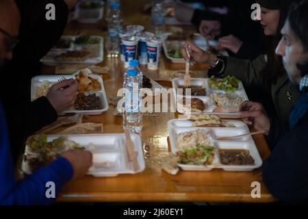 26 aprile 2022, Hessen, Francoforte sul meno: La gente mangia nel Bahnhofsviertel durante la rottura del digiuno del 5th organizzata dall'iniziativa gemeinsames Fastenbrechen. Nella sezione Elbestraße tra Münchenerstrasse e Kaiserstraße, gli uomini d'affari e i ristoranti locali invitano la gente a condividere un pasto. Il mese del digiuno islamico del Ramadan continua fino alla sera del 1 maggio 2022. Foto: Sebastian Gollnow/dpa Foto Stock