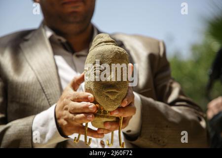 Gaza. 26th Apr 2022. Un uomo mostra una statuetta in pietra scoperta di recente, risalente al 2500 a.C. e raffigurante il volto di un'antica dea in un museo a Gaza, il 26 aprile 2022. Il Ministero del Turismo e delle Antichità a Gaza ha rivelato la statuetta in pietra trovata da un agricoltore palestinese nella striscia meridionale di Gaza, città di Khan Younis. Credit: Rizek Abdeljawad/Xinhua/Alamy Live News Foto Stock