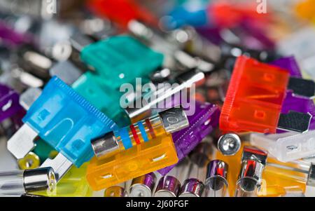 Primo piano di vari fusibili di corrente elettrica mucchio con bokeh in sfondo sfocato. Componenti elettronici di sicurezza per la protezione da sovracorrente. E-Waste heap. (Cumulo rifiuti elettronici) Foto Stock