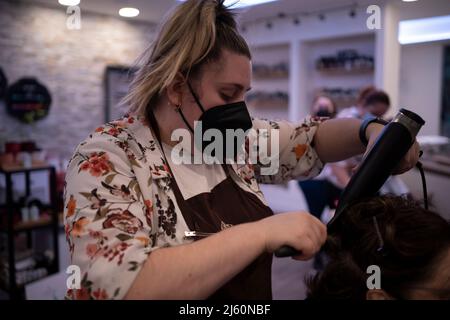 Stylist capelli asciugare i capelli del cliente con un pettine e asciugacapelli Foto Stock