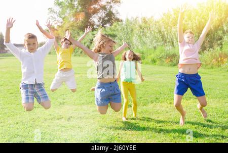 I bambini saltano e alzano le mani Foto Stock