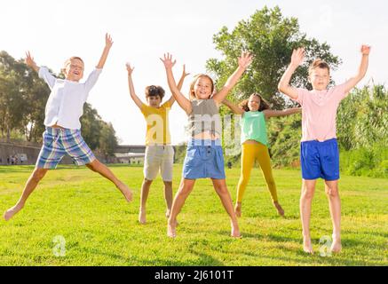 I bambini saltano e alzano le mani Foto Stock