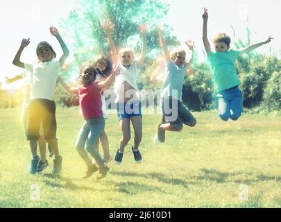 Felice squadra di amici bambini che saltano insieme nel parco Foto Stock
