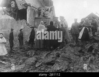 Soldati britannici e civili francesi in piedi in un villaggio in rovina. Foto Stock