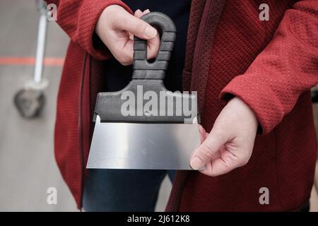 Donna in un negozio di materiali da costruzione acquista una spatola per applicare stucco sulle pareti Foto Stock