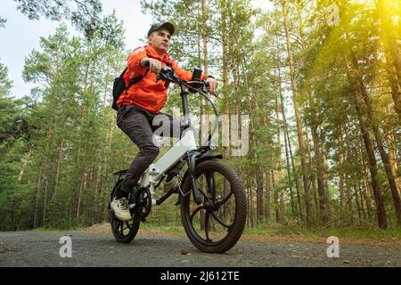 Concetto di sport. Ciclista in sella a una pista singola. A cavallo di una bicicletta elettrica moderna. Moto alla moda con cerchi in lega. Un ciclista corre contro t Foto Stock