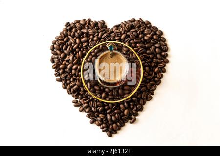 Cuore costituito da chicchi di caffè. Il concetto di amore per il caffè, la mania del caffè. Chicchi di caffè arrosto disposti a forma di cuore su uno sfondo bianco Foto Stock