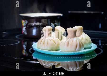 Dampling georgiano tradizionale noto come khinkali in georgiano su piastra nera su sfondo nero Foto Stock