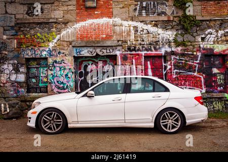 Berlina Mercedes bianca parcheggiata di fronte all'edificio abbandonato coperto di graffiti - Victoria, Vancouver Island, British Columbia, Canada Foto Stock