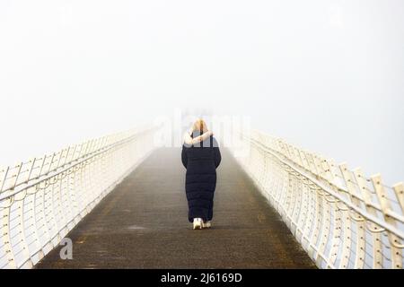 Donna che cammina in una fredda e nebbia mattina sul punto Ogden Breakwater - Victoria, Vancouver Island, British Columbia, Canada Foto Stock